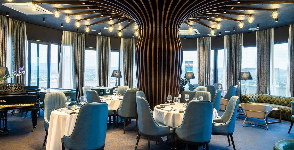 The Segreto restaurant in daylight, with a grand piano and floor-to-ceiling windows