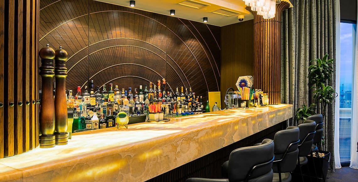 The bar, with a backlit onyx counter and an arched timber ceiling