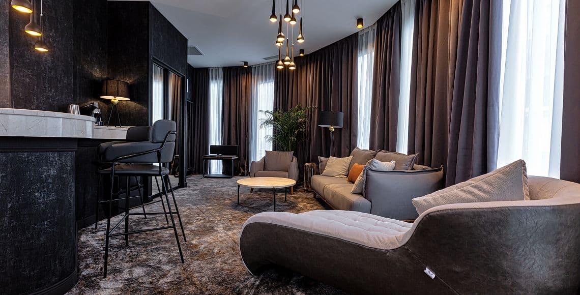 The lounge area of a suite, with a chaise longue, sofa and marble-topped bar counter