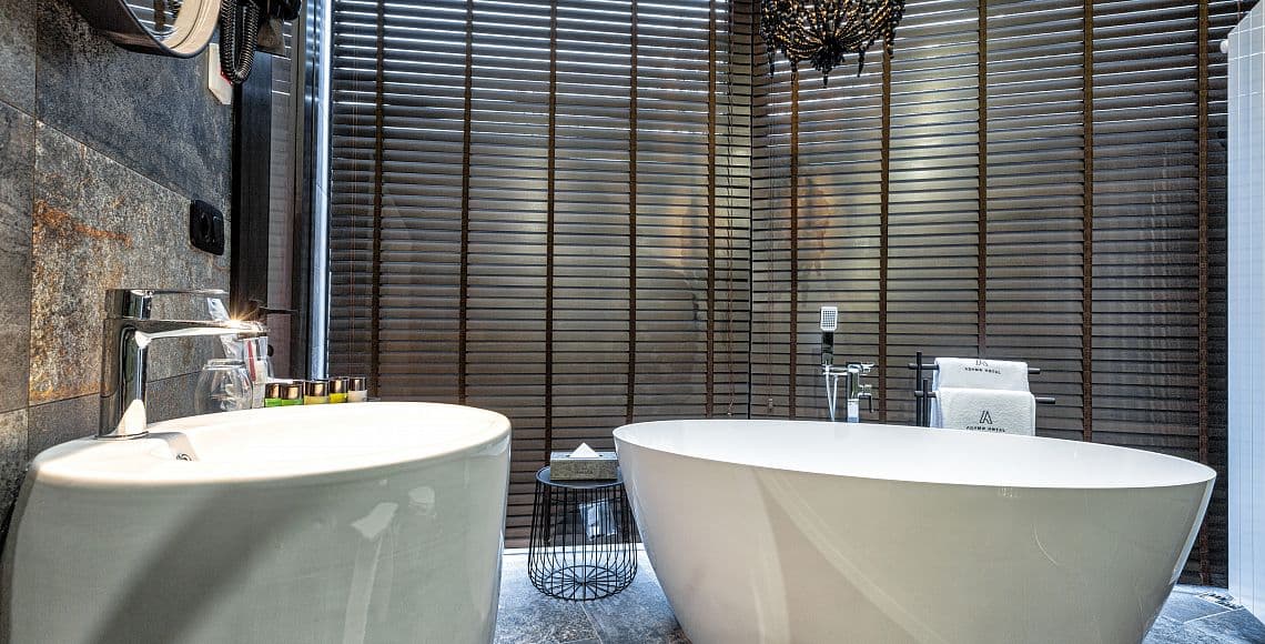 A bathroom with twin freestanding baths and a beaded chandelier