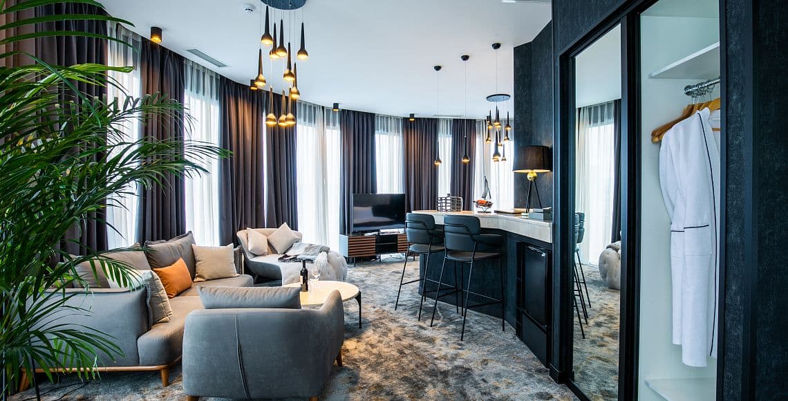 A suite lounge with clustered pendant lights and a bar counter with stools