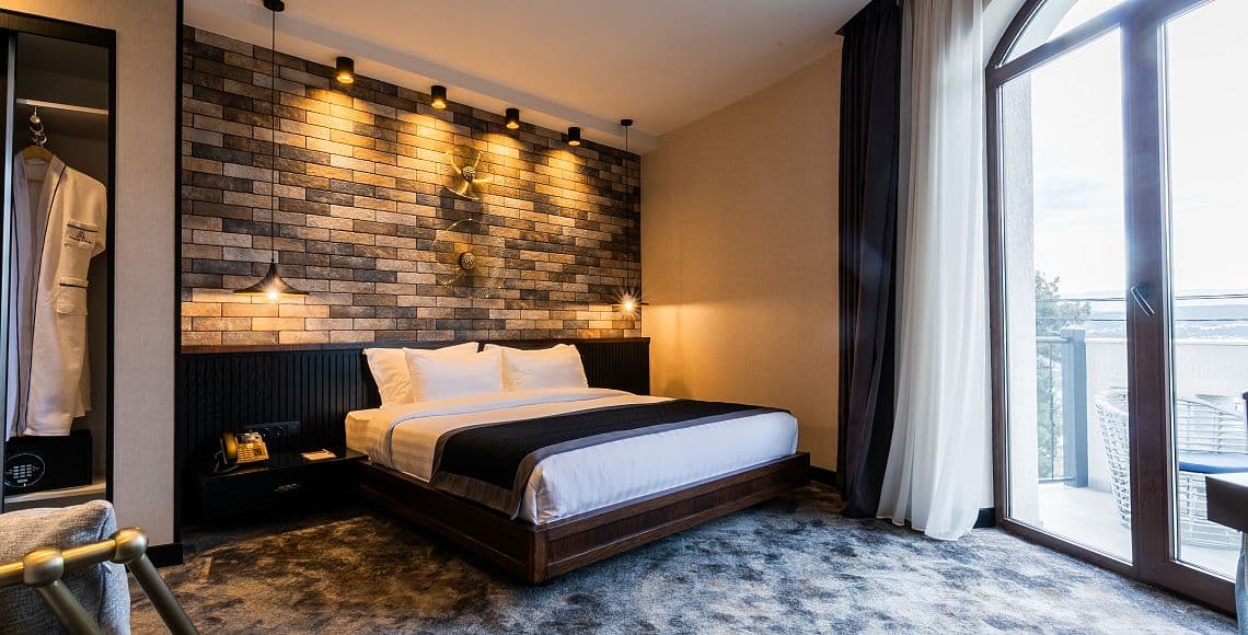 A double room with a brick feature wall, gold wall sculptures and balcony doors